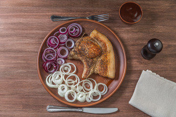 Fried pork chop with onion on the plate. The view from the top. Copyspace.