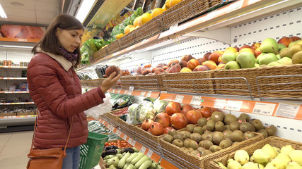 Woman in supermarket selects fruit and vegetables.