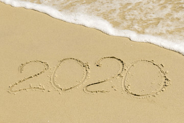 2020 inscription on sand with sea foam