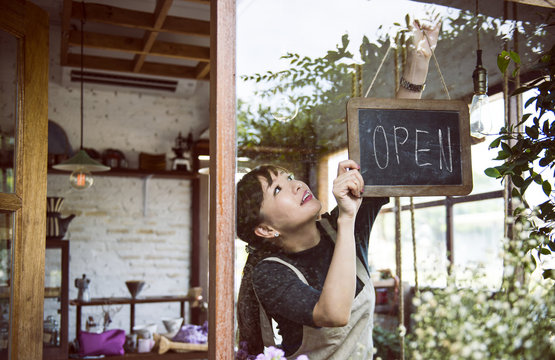 Woman hanging an open sign - Powered by Adobe