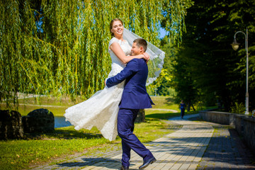 Young happy wedding couple dancing and having fun in sunny wedding day. Groom spinning bride. Dress develops in the wind. Groom holding happy emotional bride. The bride is the size of the plus size. 