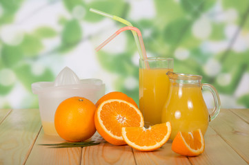 Oranges and jug of juice on wooden table