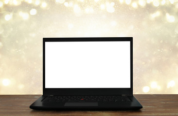 open laptop with white screen on wooden table in front of abstract glitter background