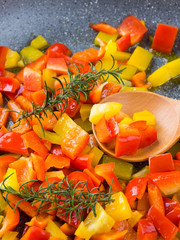 Cooking bell peppers with rosemary in frying pan