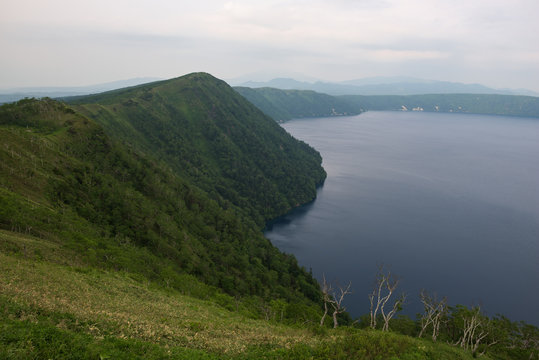Green slopes surrounding the beautiful and deep blue Lake Mashu, Hokkaido, Japan