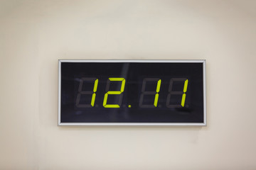 Black digital clock on a white background showing time twelve hours eleven minutes