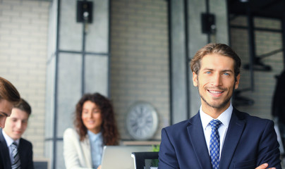 Businessman with colleagues in the background in office.