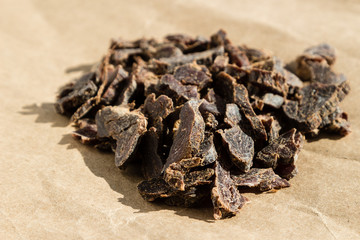 Biltong (protein snack) on brown paper, this is a traditional food snack that can be found in South Africa. This image has selective focusing.