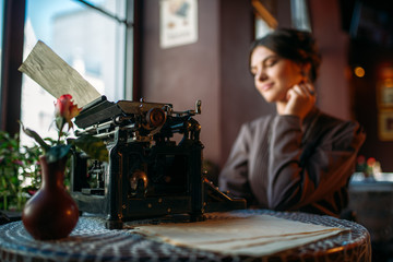 Smiling lady sits by table with ancient typewriter