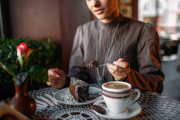 Woman eating delicious chocolate cake in cafe