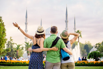 Obraz premium Group of Friends hugging and looking at Istanbul great Blue Mosque. Student travel in Turkey concept
