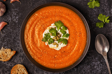 Pumpkin and carrot soup with cream, seeds and parsley.