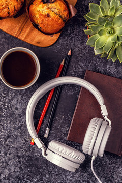 Table with notepad, headphones and coffee.
