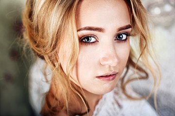 Naklejka premium Beautiful young bride with wedding makeup and hairstyle in bedroom, newlywed woman final preparation for wedding. Happy Bride waiting groom. Marriage Wedding day moment. Bride portrait soft focus