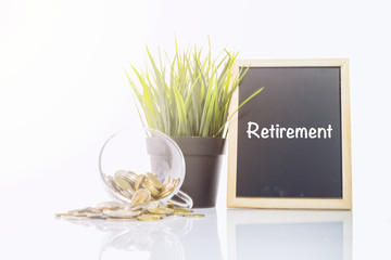 Coin in glass, green plant and chalkboard with word RETIREMENT on reflection table ideal for saving and investment concept