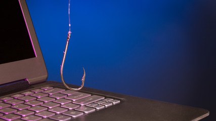 fish hook hanging above a laptop keyboard