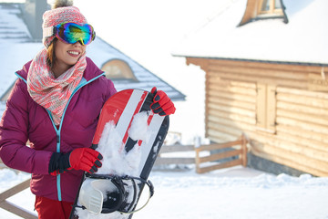 Picture of happy young lady snowboarder on the slopes frosty winter day. Look at camera.