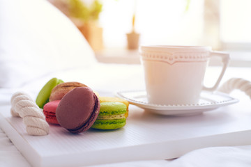 Colorful macaroons with a cup of coffee isolated on tray