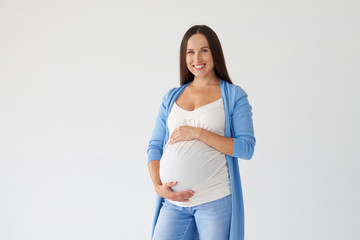 Young pregnant woman posing with hands on belly