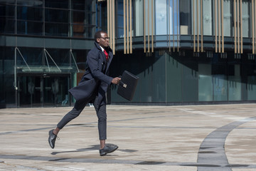 Full-length portrait of dark-skinned African entrepreneur wearing black coat and formal clothes,...
