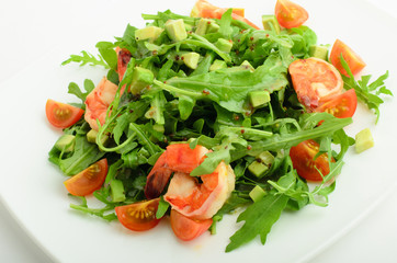 Salad with shrimps, avocado, cherry tomatoes and arugula on a plate isolated on white background