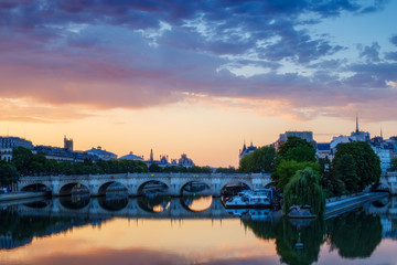 Naklejka premium Sunrise over Paris, France with Pont Neuf and the river Seine. Colourful skyline with dramatic clouds.