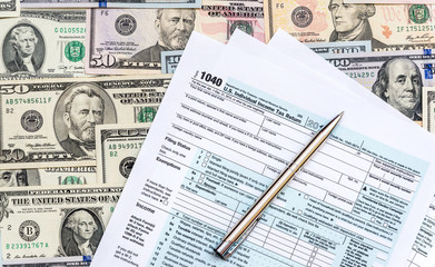 Tax form with pen on background of dollar bills. Business concept.