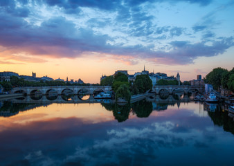 Fototapeta premium Sunrise over La Cite in Paris, France with Pont Neuf and the river Seine. Colourful travel background. Romantic cityscape.