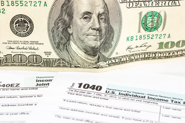Tax form with one hundred dollar bill. close up.