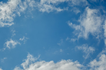 Background of transparent white clouds in a light blue sky illuminated by the setting sun.