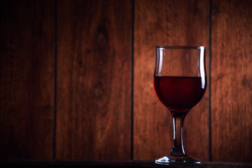 A glass of red wine on an old wooden background