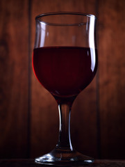 A glass of red wine on an old wooden background