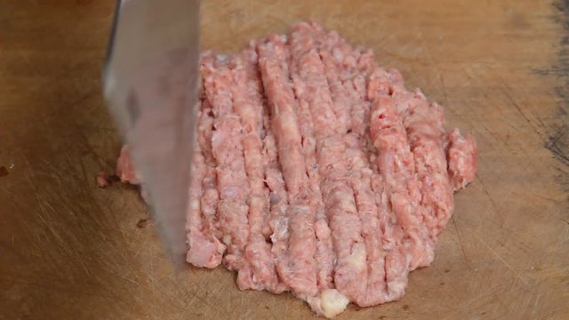 cleaver chop to raw pork for minced on wooden cutting board