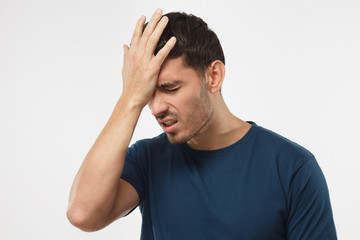 Close up portrait of young man with face palm gesture. Disappointed stressed out male in blue...