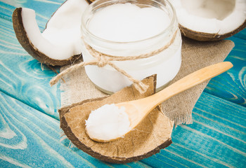 Coconut oil and fresh coconuts on a wooden table.