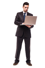 Front view of young bearded corporate man working on laptop. Full body length portrait isolated over white studio background.