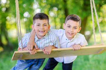 two smiling brothers, ride on a swing and embrace.