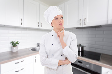 young attractive woman chef dreaming in modern kitchen