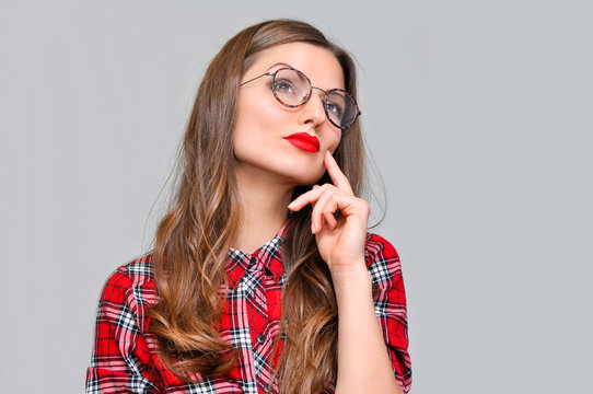 Portrait of beautiful young woman in a red plaid shirt and round glasses. She thought and looking in the direction