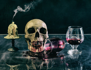 Skull with blood glass and candle in Halloween night