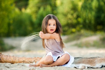 beautiful little girl on the beach playing with sand and having fun.