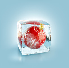 Beautiful red Christmas ball inside ice cube.