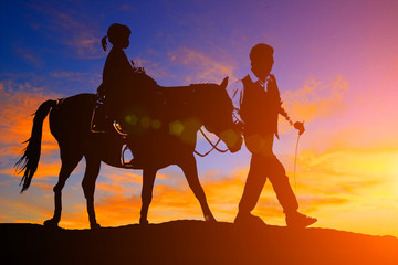 silhouette cowboy and horse on blurry colorful sunset sky.