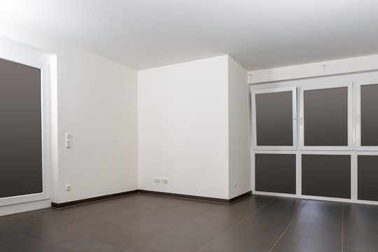 Leerer weißer Raum mit großen breiten Fenstern und schwarzen Fliesen