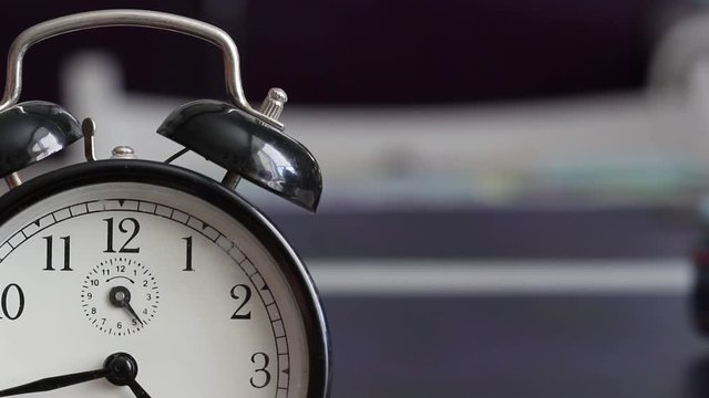 Vintage alarm clock is ringing on blurred background.