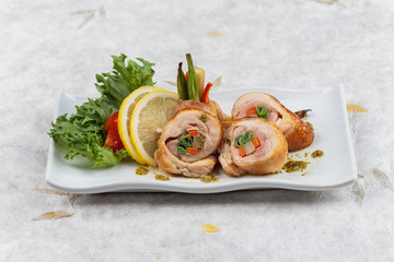 Stir fried chicken wrap with carrot. scallion and radish served with sliced lemon, tomato and lettuce in white ceramic plate on washi (Japanese paper).