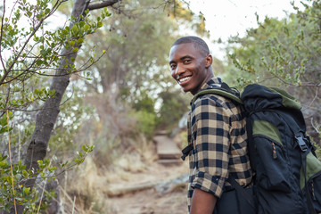 Naklejka na ściany i meble Smiling young African man hiking in the hills