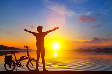 Fototapeta na wymiar Silhouette man and bike relaxing with sunrise background.