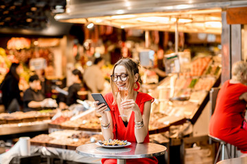 Young woman in red dress having lunch with mussels and rose wine sitting at the food market
