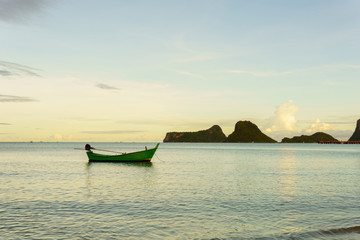 beautiful panorama landscape of silhouette fisherman boat floating in sea at the beach at dusk and reflection on sea. boat in the sea in evening when sunset with golden light with mountain background.